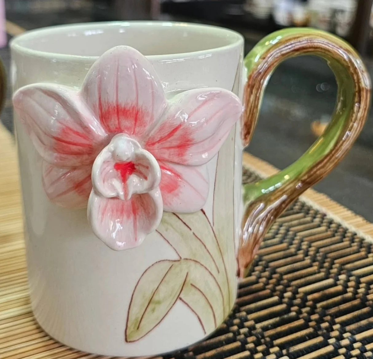 Handcrafted ceramic mug with a raised pink orchid